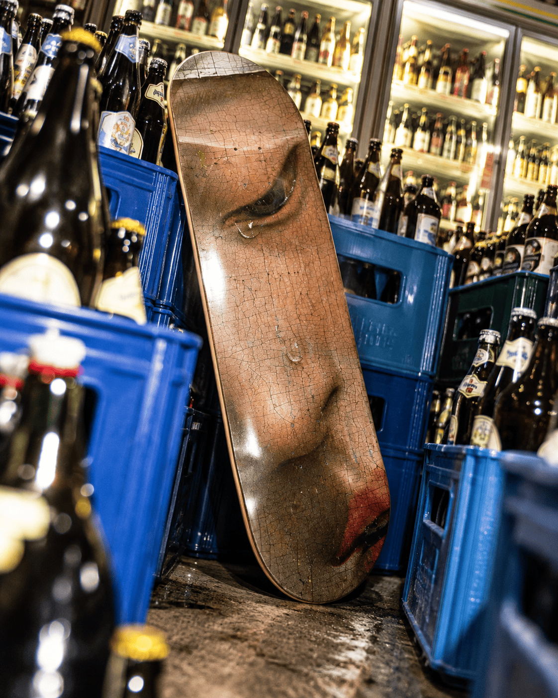 Weeping Muse skateboard deck leaning against blue crates in a German beverage store, refrigerated drinks visible behind