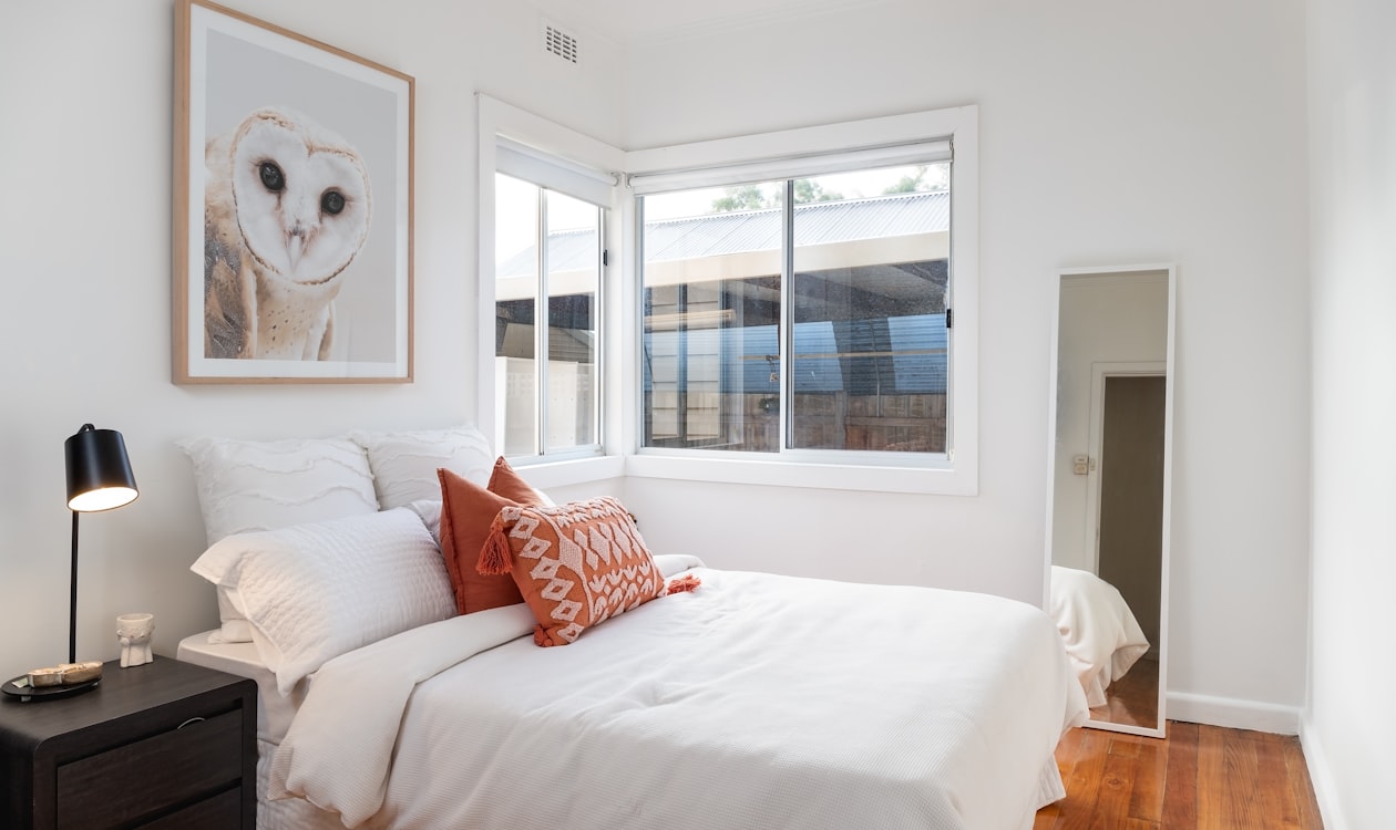 Minimal bedroom with white bed and painting on the wall — wall art for bedroom placement guide — DeckArts classical art decks Berlin