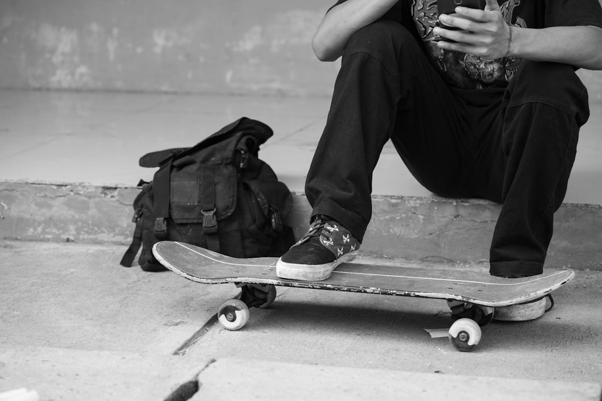 a man sitting on a skateboard next to a bag